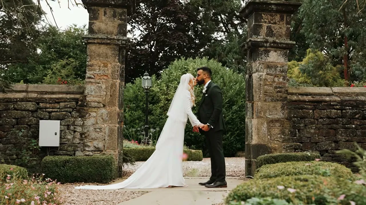 Agnes and her partner sharing a kiss beneath a stone archway