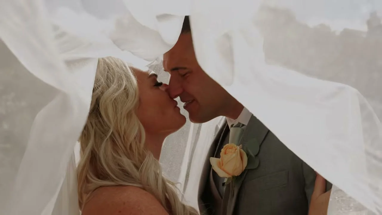 Daniel and Nikki sharing a kiss beneath the wedding veil