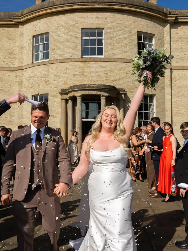 Bride and groom walk through confetti outside Stubton Hall