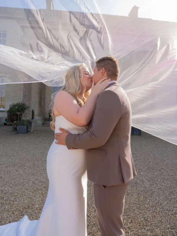 Bride and groom kiss beneath her flowing veil at Stubton Hall